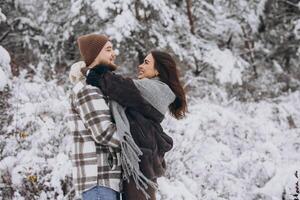 Portrait of a young happy and loving couple having fun in a snowy forest photo