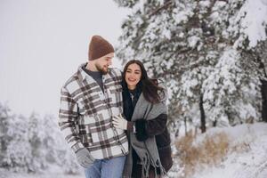 A young happy and loving couple walking in a winter snowy forest in the mountains photo