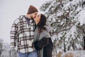 A young happy and loving couple walking in a winter snowy forest in the mountains photo