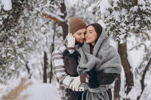 Portrait of a young happy and loving couple having fun in a snowy forest photo