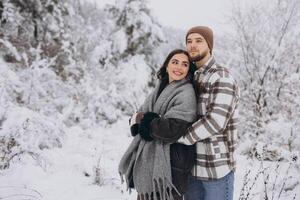 Portrait of a young happy and loving couple having fun in a snowy forest photo