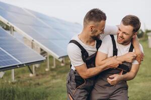 Two happy bearded gay in work uniforms joying and flirting with each other hugging on the background of solar panels photo