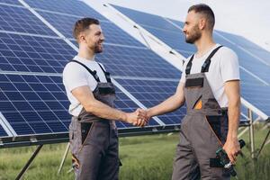 Two bearded workers in overalls shake hands after completing a panel plan photo