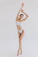 Full-length image of sensual, beautiful young woman with slim body shape posing in elegant white lingerie isolated on white background. photo