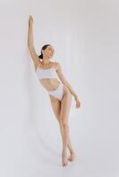Full-length portrait of beautiful woman with slim body in underwear posing in the white studio background with copy space, mock-up photo