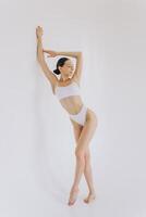 Full-length portrait of beautiful woman with slim body in underwear posing in the white studio background with copy space, mock-up photo