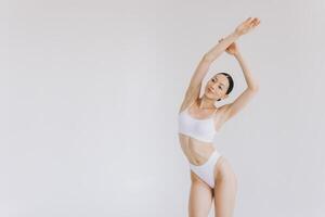 Portrait of beautiful woman with slim body in underwear posing in the white studio background with copy space, mock-up photo