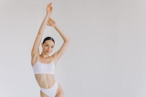 Portrait of beautiful woman with slim body in underwear posing in the white studio background with copy space, mock-up photo