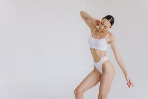 Portrait of beautiful woman with slim body in underwear posing in the white studio background with copy space, mock-up photo