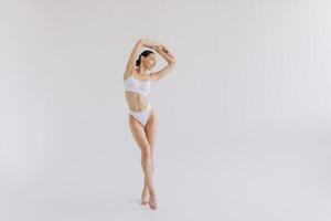 Full-length portrait of beautiful woman with slim body in underwear posing in the white studio background with copy space, mock-up photo