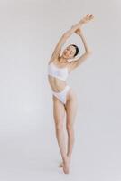 Full-length portrait of beautiful woman with slim body in underwear posing in the white studio background with copy space, mock-up photo