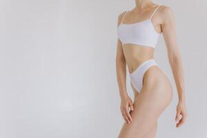 Close up view. Beautiful woman with slim body in underwear posing in the white studio background. photo