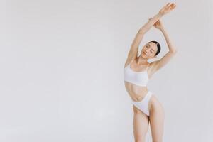 Portrait of beautiful woman with slim body in underwear posing in the white studio background with copy space, mock-up photo