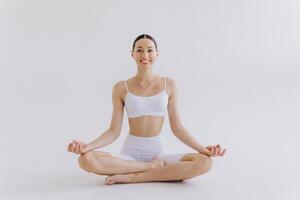 Sporty young woman with slim body doing yoga practice isolated on white background - concept of healthy life and natural balance between body and mental development photo