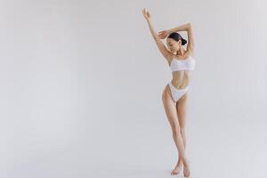 Full-length portrait of beautiful woman with slim body in underwear posing in the white studio background with copy space, mock-up photo