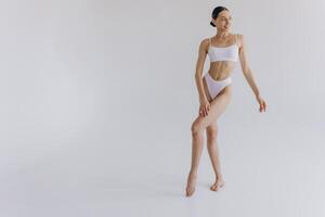 Full-length portrait of beautiful woman with slim body in underwear posing in the white studio background with copy space, mock-up photo