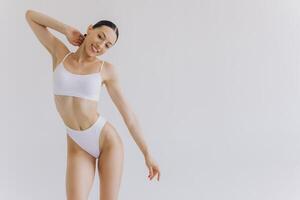 Portrait of beautiful woman with slim body in underwear posing in the white studio background with copy space, mock-up photo