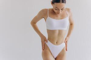Close up view. Beautiful woman with slim body and perfect stomach in underwear posing in white studio background. photo