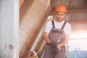 Process of construction new and modern modular house. Worker man in special protective uniform puts gloves and working on building development industry of energy efficient property. photo