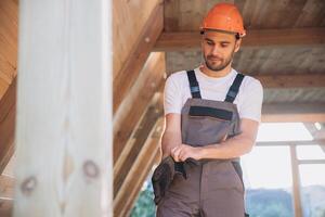 Process of construction new and modern modular house. Worker man in special protective uniform puts gloves and working on building development industry of energy efficient property. photo