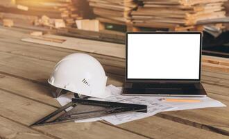 Top view mock -up architectural office desk with copy space, wooden floor with laptop, white helmet construction, pencil, ruler and paper roll, copy space, mock up photo