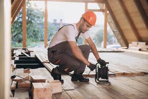 Process of construction new and modern modular house. Worker man in special protective uniform unrolls the carrier on building development industry of energy efficient property. photo
