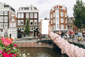 Female tourist taking photo with mobile phone in Amsterdam, Netherlands. Mockup concept