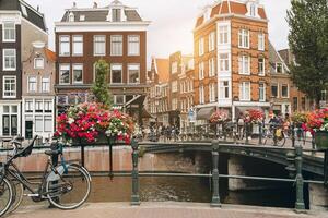 Old bicycle on the bridge in Amsterdam, Netherlands against a canal during summer sunny day. Postcard iconic view. Tourism concept. photo