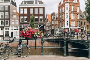 Old bicycle on the bridge in Amsterdam, Netherlands against a canal during summer. Postcard iconic view. Tourism concept. photo