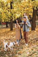 Happy young family walks and plays with a dog in the autumn park photo