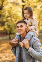 Happy dad and little daughter walking in autumn park, father's day concept photo