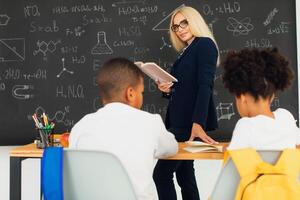 A girl and a boy, African-American school children, solve problems with the teacher during a lesson. Back to school. photo