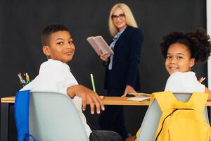 A girl and a boy, African-American school children, solve problems with the teacher during a lesson. Back to school. photo