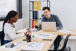 Young African beautiful woman having an interview or business meeting with employer. Employer examining in a modern office interior photo