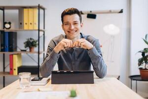 Young man sitting in office and working on desktop pc. Businessman looking at computer monitor while working in office. photo