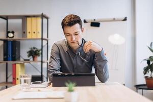 Young man sitting in office and working on desktop pc. Businessman looking at computer monitor while working in office. photo