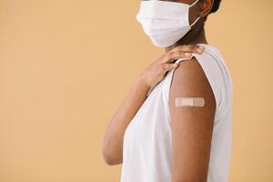 Smiling Multiethnic Patients In Medical Face Mask Showing Vaccinated Arm After Antiviral Injection For Covid-19 Protection, Posing On Studio Background, Looking At Camera photo