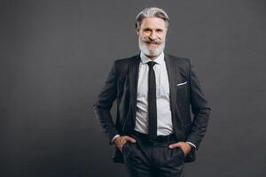 Portrait of a stylish and fashionable mature man in a gray suit. Business and trendy close-up concept on the grey background. photo