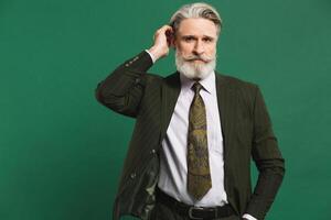 Stylish bearded middle-aged man in khaki suit on green background photo