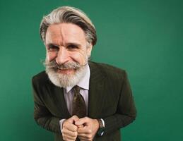 Stylish bearded middle-aged man in khaki suit holds hands together closeup on green background photo