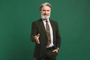 Middle-aged bearded man in khaki suit hand greetings on green background photo