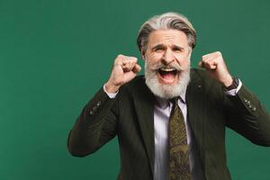 A middle-aged bearded man in a khaki suit shouts loudly and holds his fists against on a green background photo