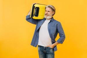 Stylish laughing bearded man holding a yellow suitcase. photo