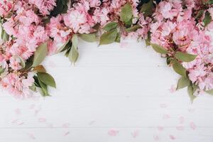 Sprigs of the sakura tree with flowers and petals on a wooden white background. Place for text. The concept of spring came. Top view. Flat lay photo