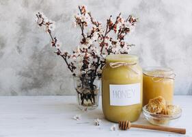 Spring composition, fresh honey with honeycomb, blooming cherry on a flat lay background photo