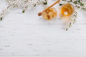 Spring composition. A cup of herbal tea and a jar of honey on a white wooden background, cherry flowers top view. Place for text. Healthy food concept. photo