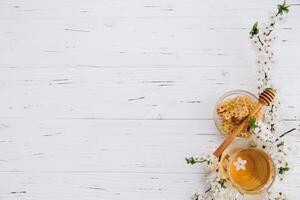 Spring composition. A cup of herbal tea and a jar of honey on a white wooden background, cherry flowers top view. Place for text. Healthy food concept. photo