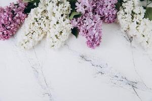 Floral pattern of a branch of lilac on a trendy marble background. Top view. Flat lay. Spring concept. Copy space photo