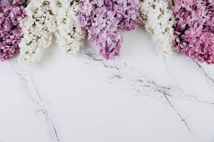 Floral pattern of a branch of lilac on a trendy marble background. Top view. Flat lay. Spring concept. Copy space photo