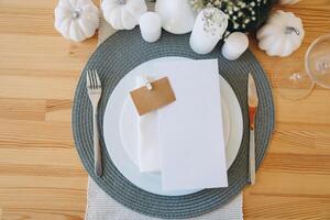 Thanksgiving table setting, tableware and decorations. Blank white postcard on table mockup. photo